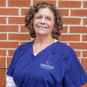 Nurse wearing scrubs with Griswold logo in front of a brick wall